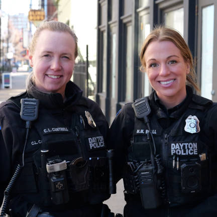 Two female Dayton Police Officers smiling on downtown city street.